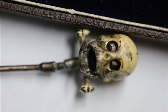 A 19th century French? base metal and cream enamel skull head stick pin, in the manner of Trouve & Cadet-Picard, overall 73mm.